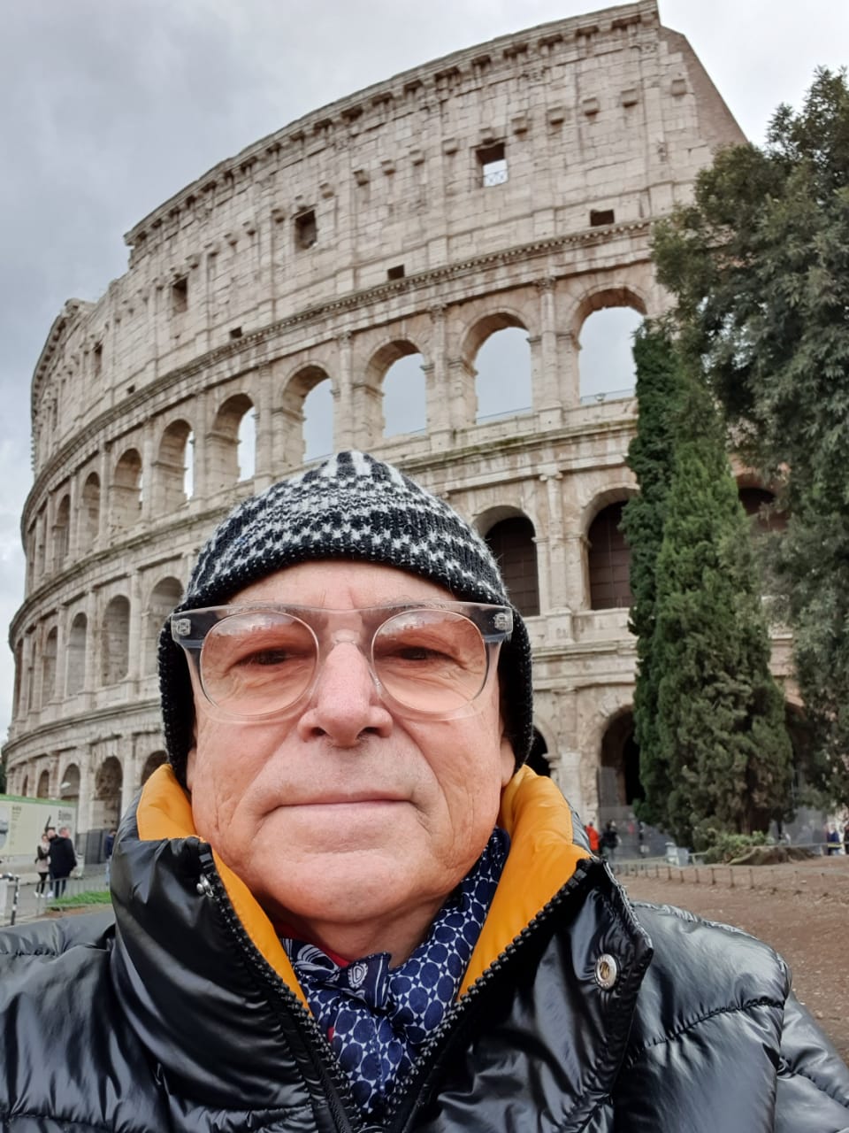 homem com roupa de frio em frente ao Coliseu de Roma